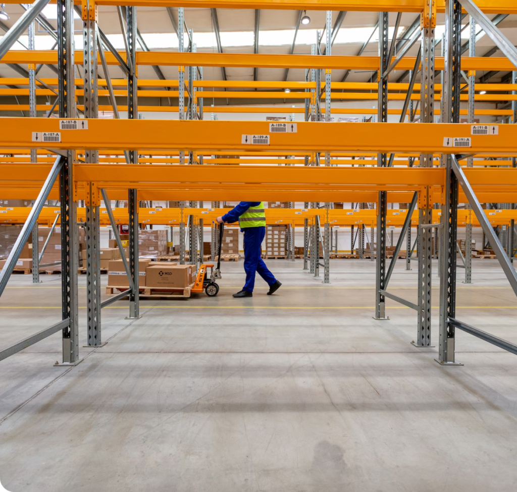 Man in Blue Uniform Pushing Trolley with Boxes in Factory.