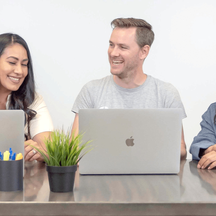 Man and Woman Smiling at Table with Laptop