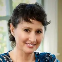 Dark short haired woman smiling in a blue shirt