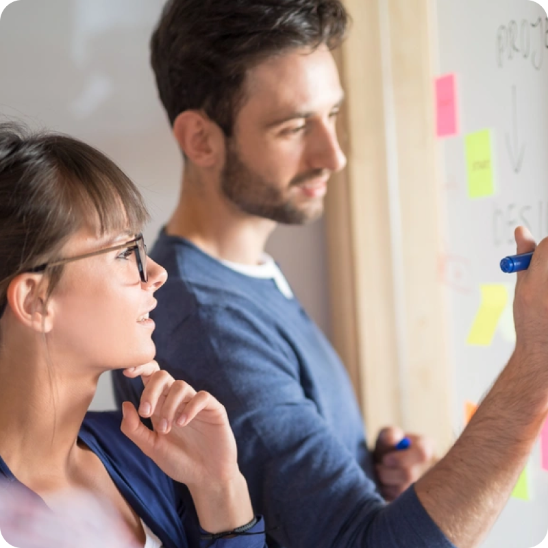 Man Writing on Whiteboard, Woman Observing