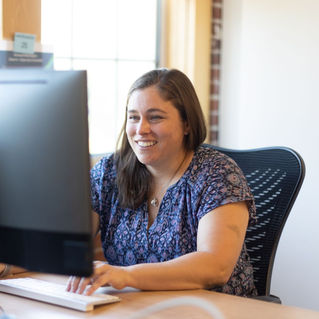 Smiling Woman Typing on Computer