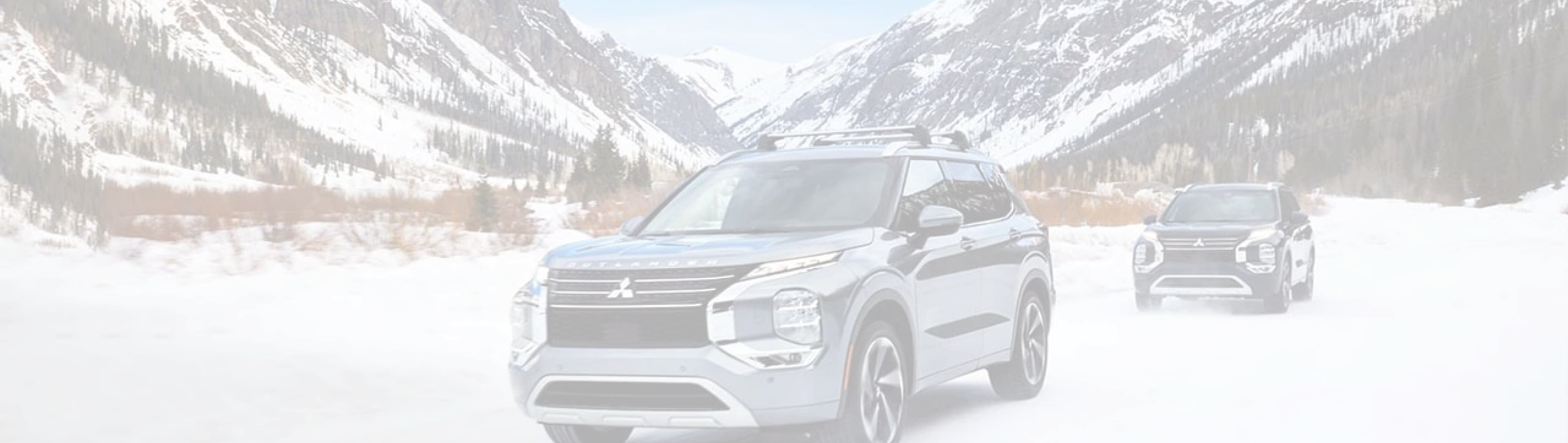 Two Mitsubishi Pickup Trucks in Snowy Mountain Landscape