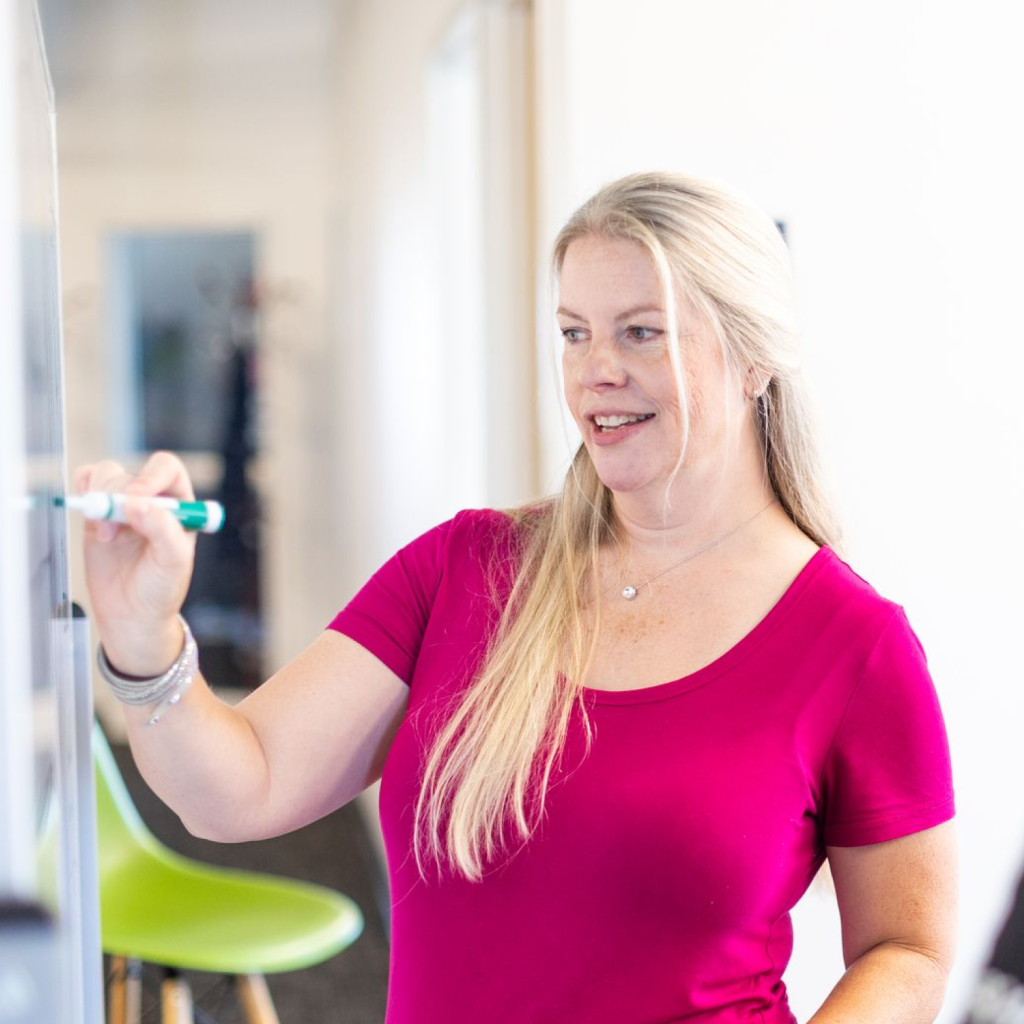 Blonde Woman in Pink Shirt Writing on Whiteboard