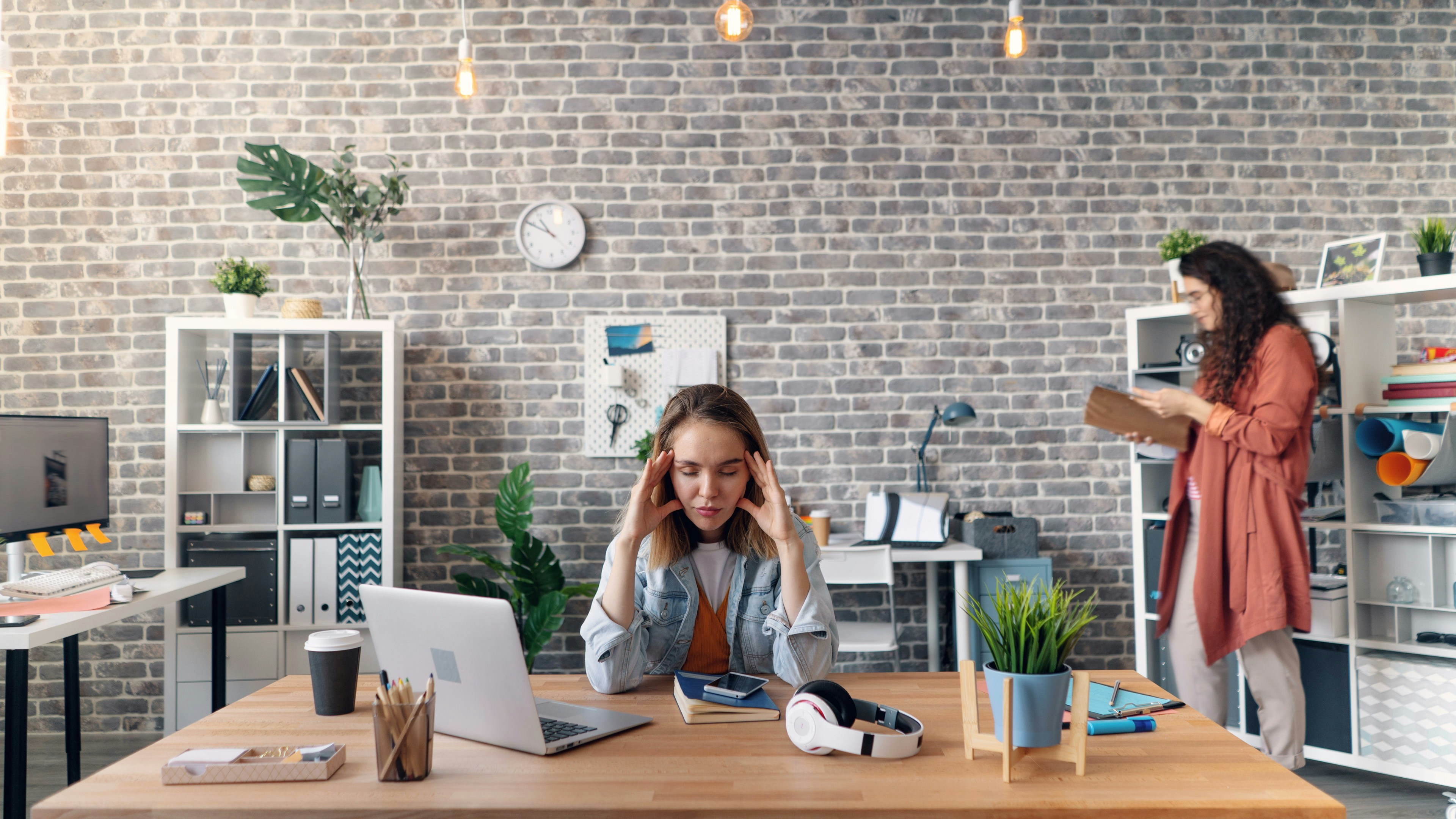 A women with her elbows propped on her desk, with her hands in her head, as if she's feeling frustrated by hiring challenges